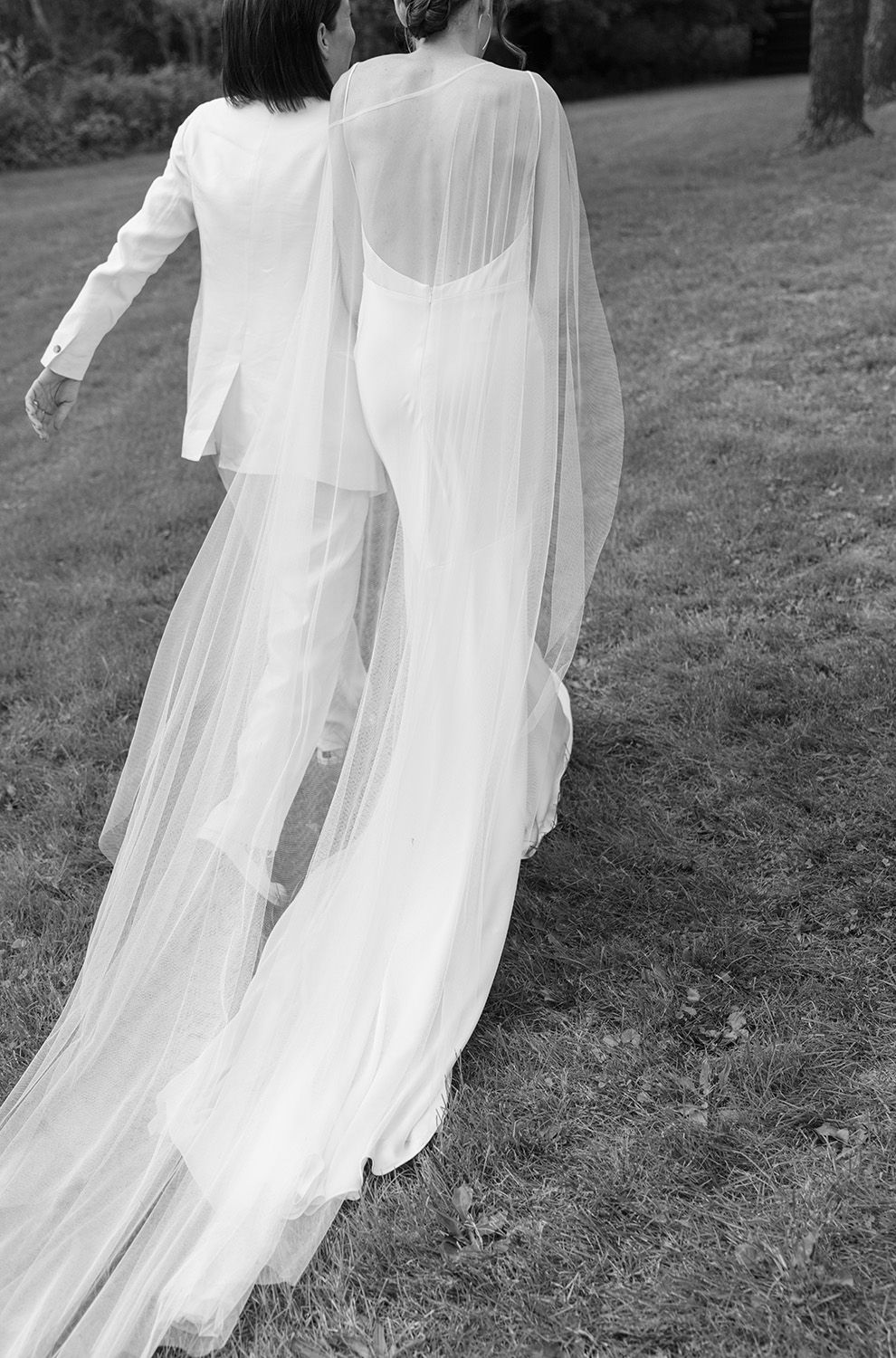 Flowing white wedding dress fabric billowing gracefully in the wind across a grassy field.