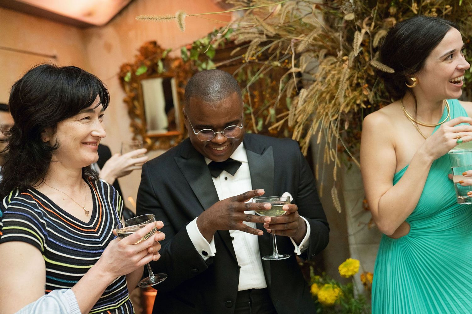 Wedding guests mingling at an elegant reception with floral decorations and ambient lighting.