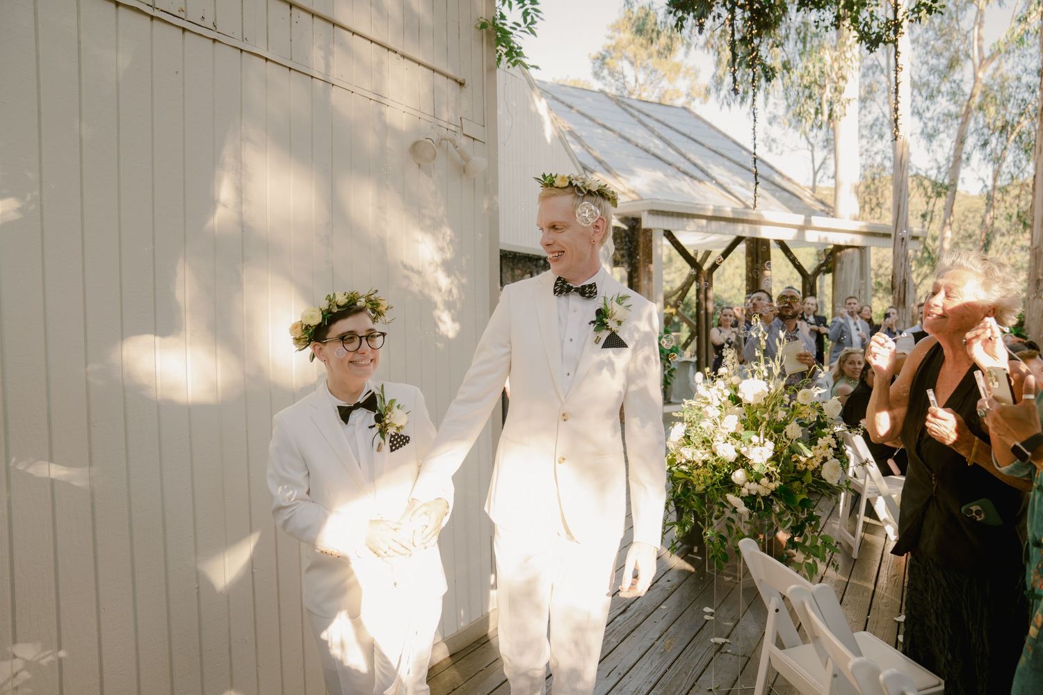 Outdoor wedding venue with white decor and natural lighting filtering through trees.