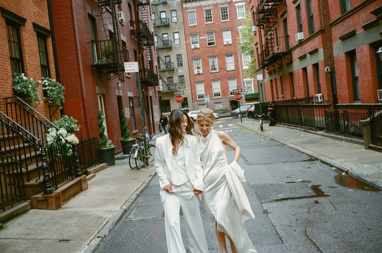 A group walks down a historic brick street lined with brownstone buildings.