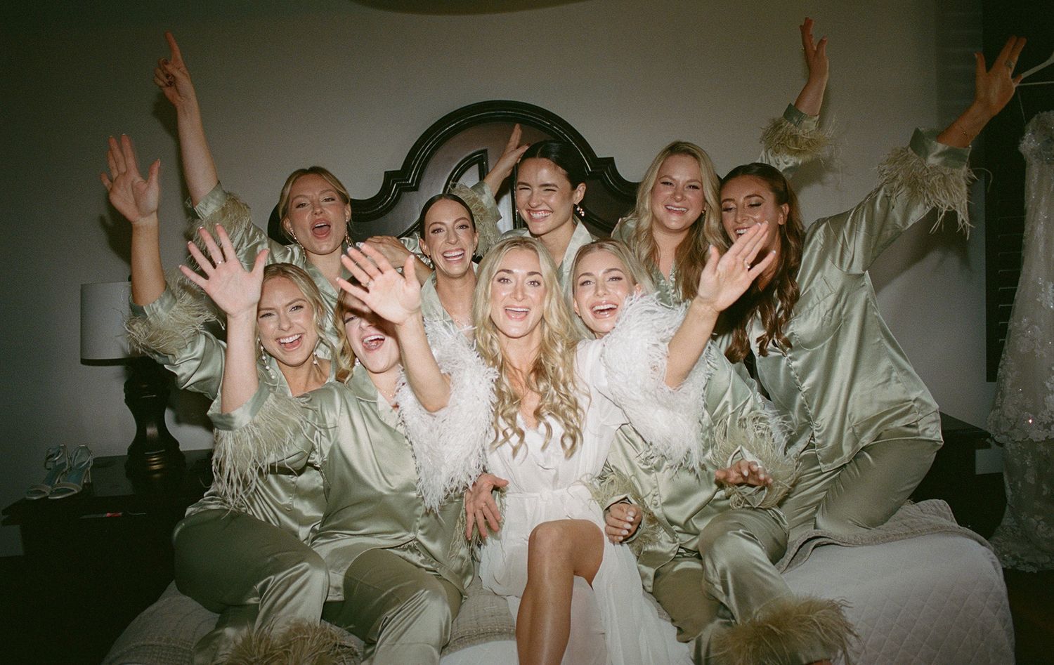 Wedding party in white robes celebrating with excited poses and gestures.