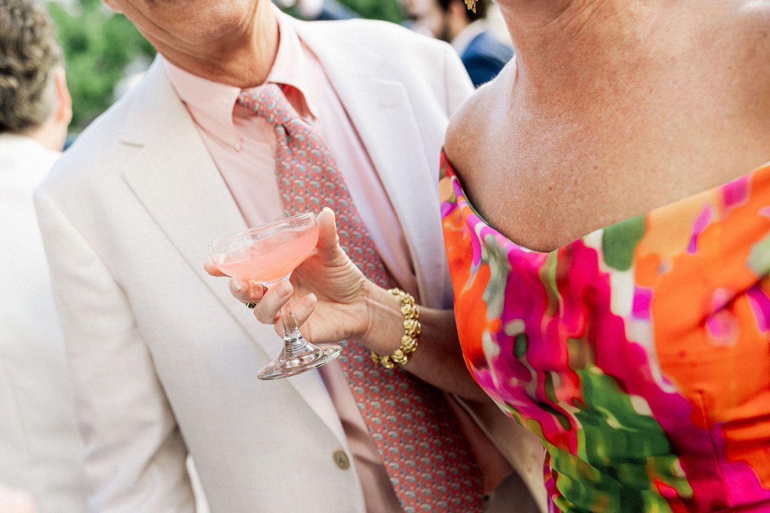 A close-up of a boutonniere being pinned on a light colored suit jacket.