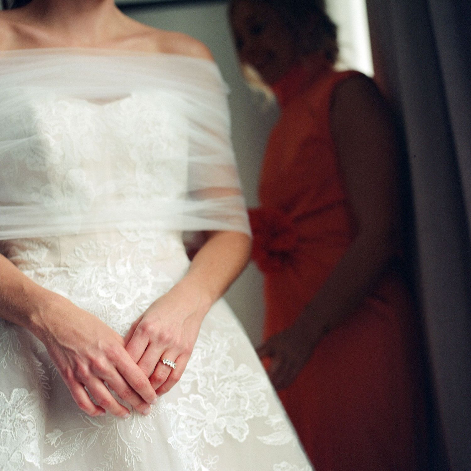 Close-up details of white wedding dress lace and fabric in soft window light.