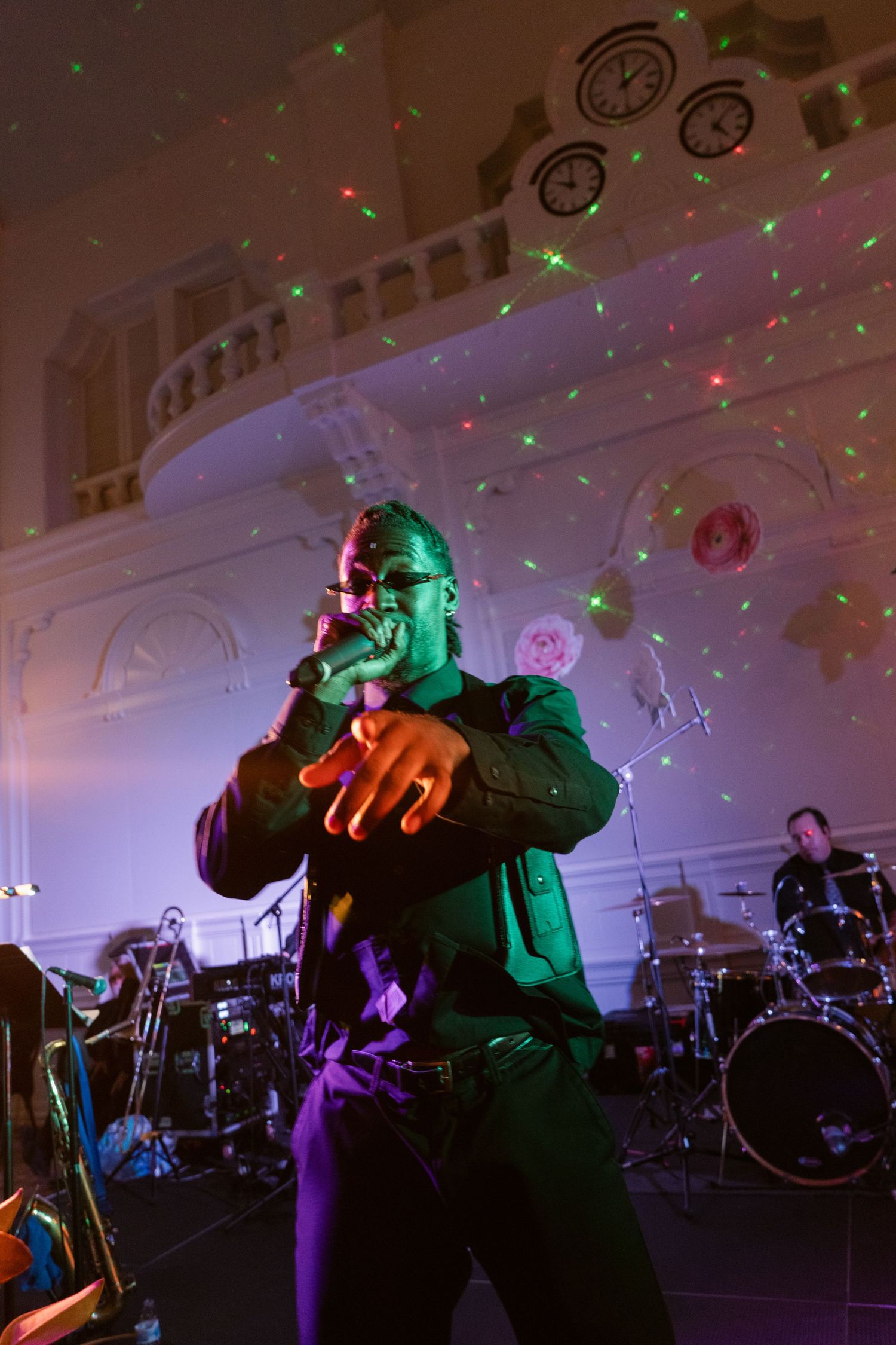 Concert performers on stage with colorful red and green lighting effects.
