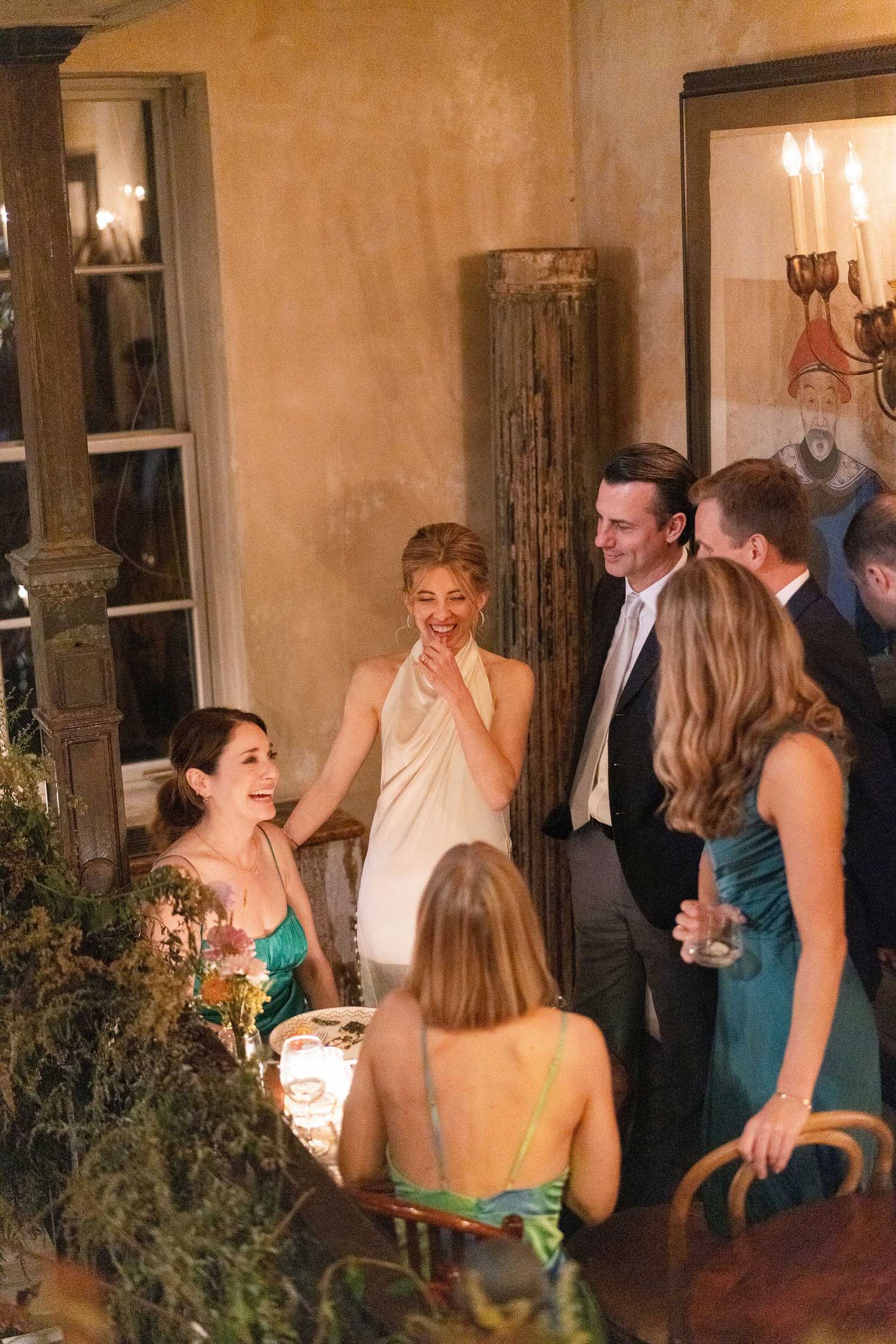 Guests laughing and socializing during an evening wedding reception.