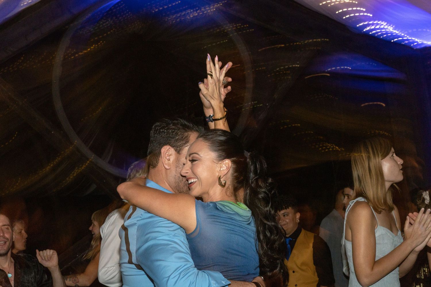 Couples dancing close together under blue ambient lighting at a formal event.