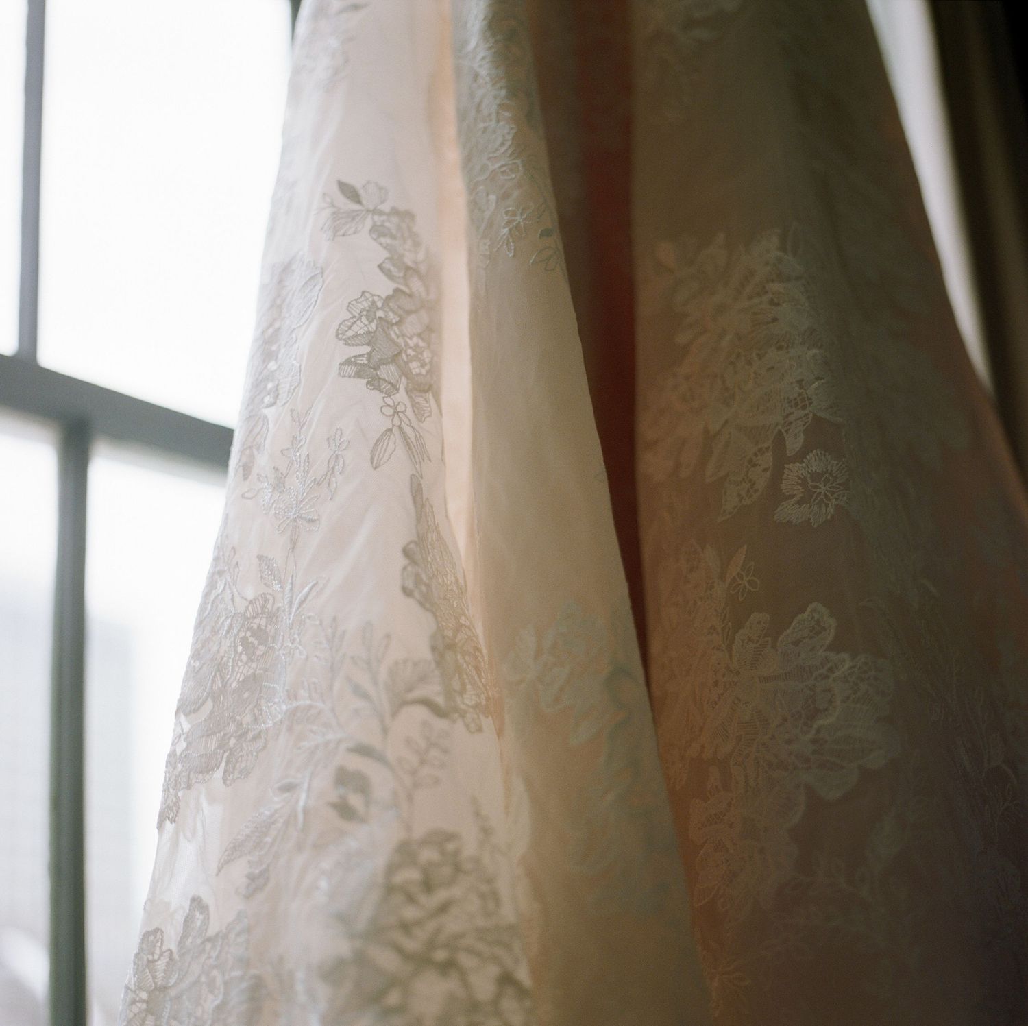 Close-up detail of delicate lace pattern on a white wedding dress fabric.