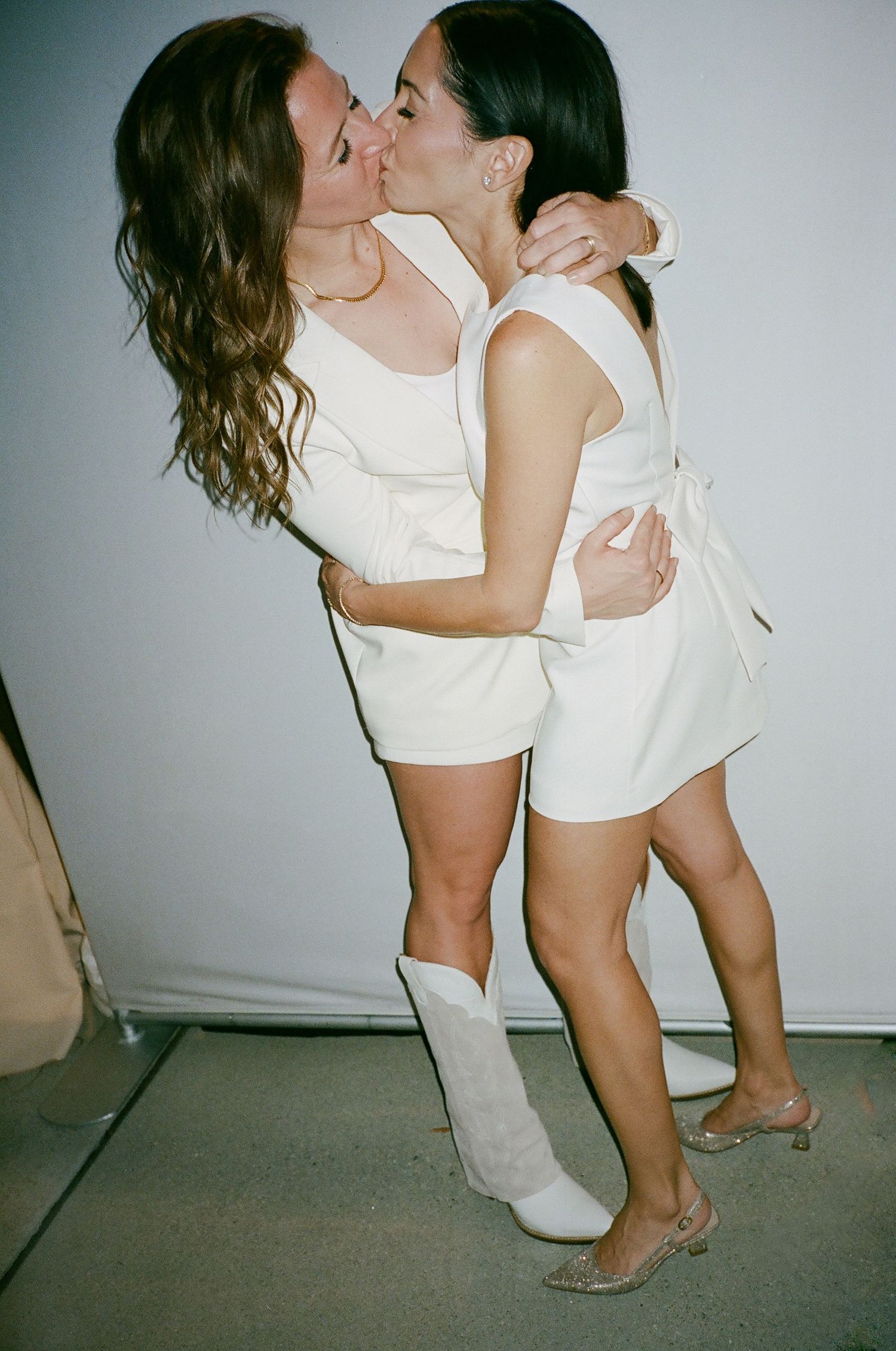 Two people in white outfits sharing an intimate dance moment against a plain background.