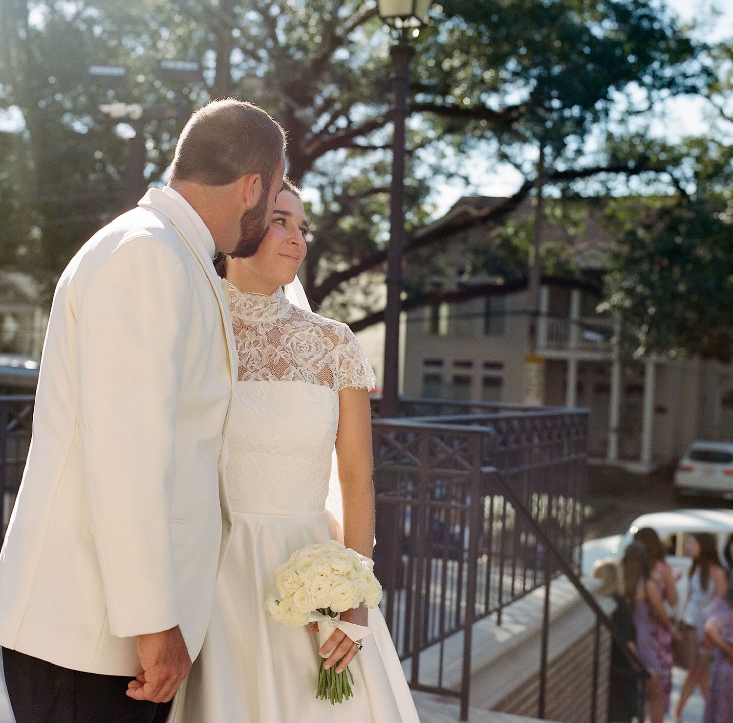 Couple walking together outdoors in elegant white wedding attire.