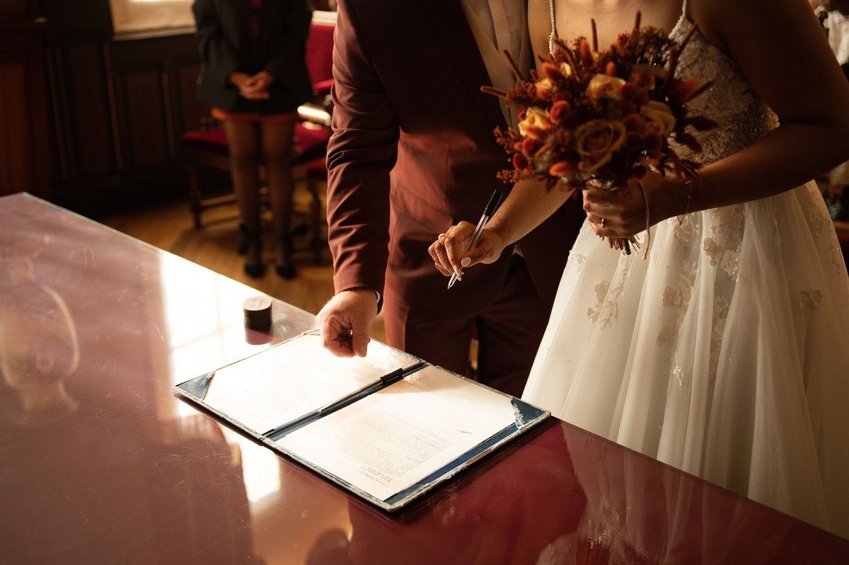 Close-up view of hands signing a wedding document with a pen during a marriage ceremony.