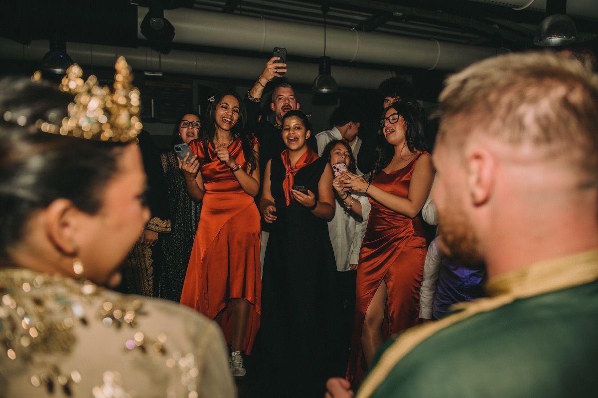 Bridesmaids in coral dresses gather around during a wedding reception celebration.