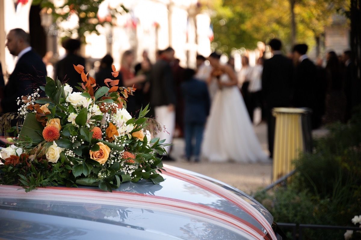 A wedding party celebrates with guests on a sunny outdoor terrace decorated with floral arrangements and elegant decor.