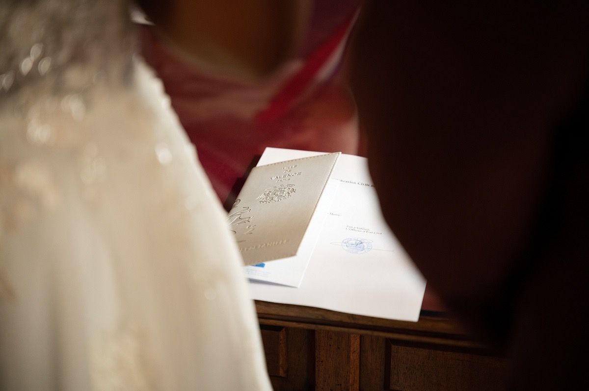 Soft focus black and white image showing the edge of a wedding dress against a dark background.