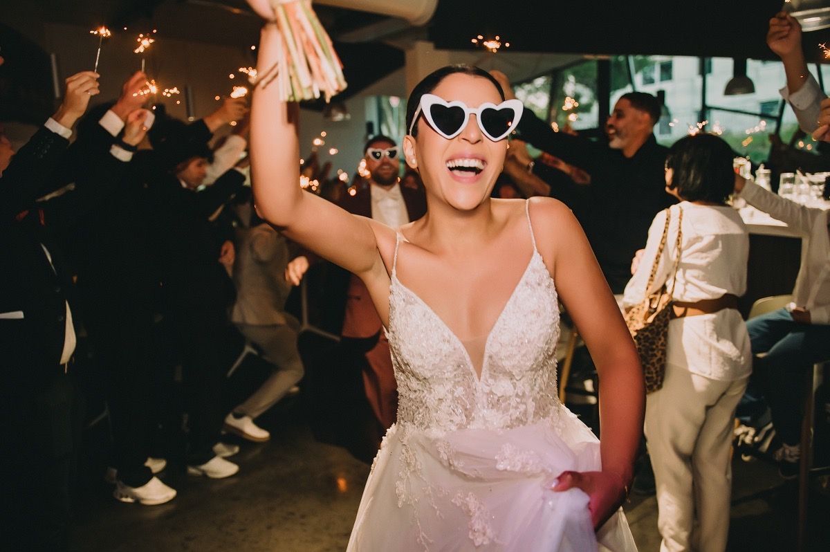 A joyful wedding celebration with dancing guests in formal attire on a dimly lit dance floor.