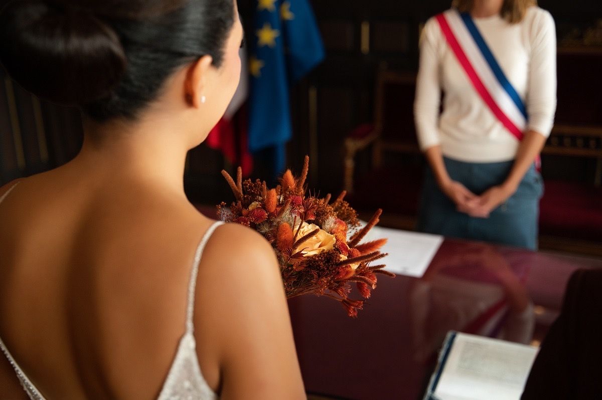 A bride and groom exchange rings during an intimate indoor wedding ceremony with warm lighting.