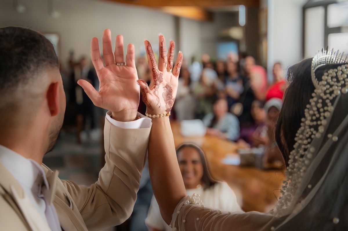 A group of people raise their hands in celebration during what appears to be a wedding reception or party.