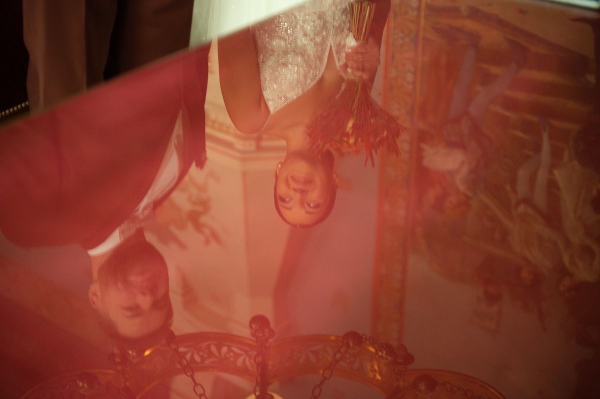Artistic red-tinted wedding photography showing silhouettes of a couple during their ceremony.