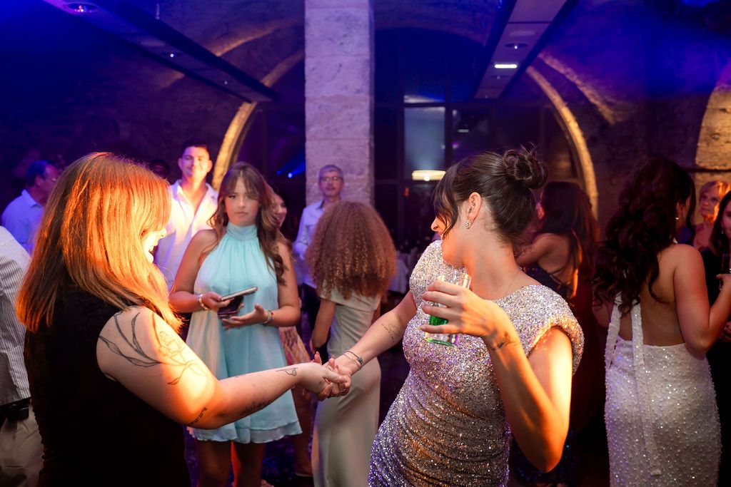 Guests dancing and socializing at an elegant indoor party with blue ambient lighting and stone arch decor.