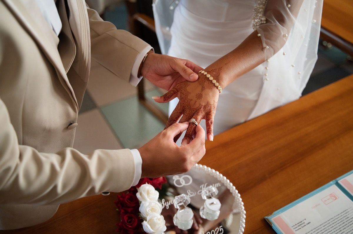 A person's hands carefully placing decorative cupcakes onto a wooden table surface.