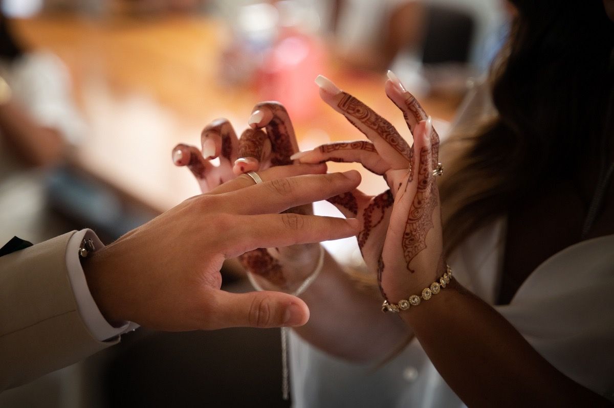 Close-up view of hands exchanging wedding rings during a marriage ceremony.