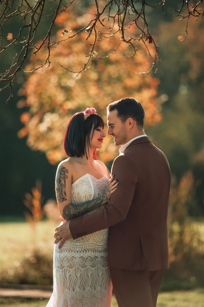 A couple shares an intimate moment in a romantic autumn setting with golden leaves and warm sunlight.
