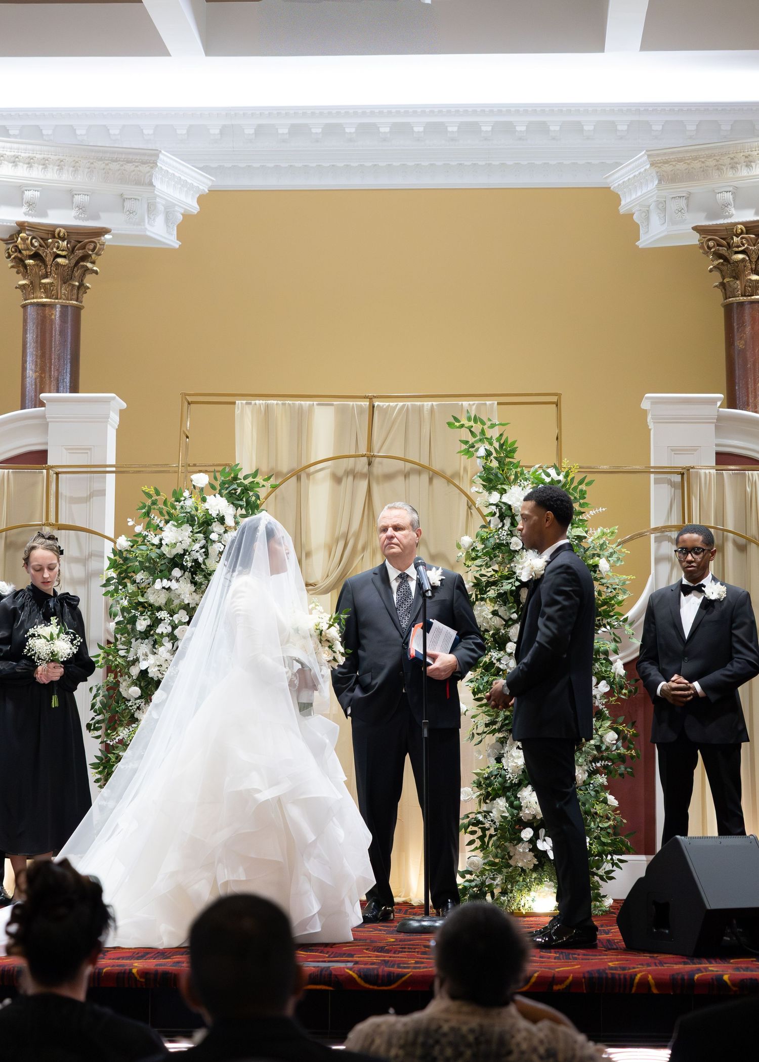 Bride and groom exchange vows at elegant wedding altar with floral arch.