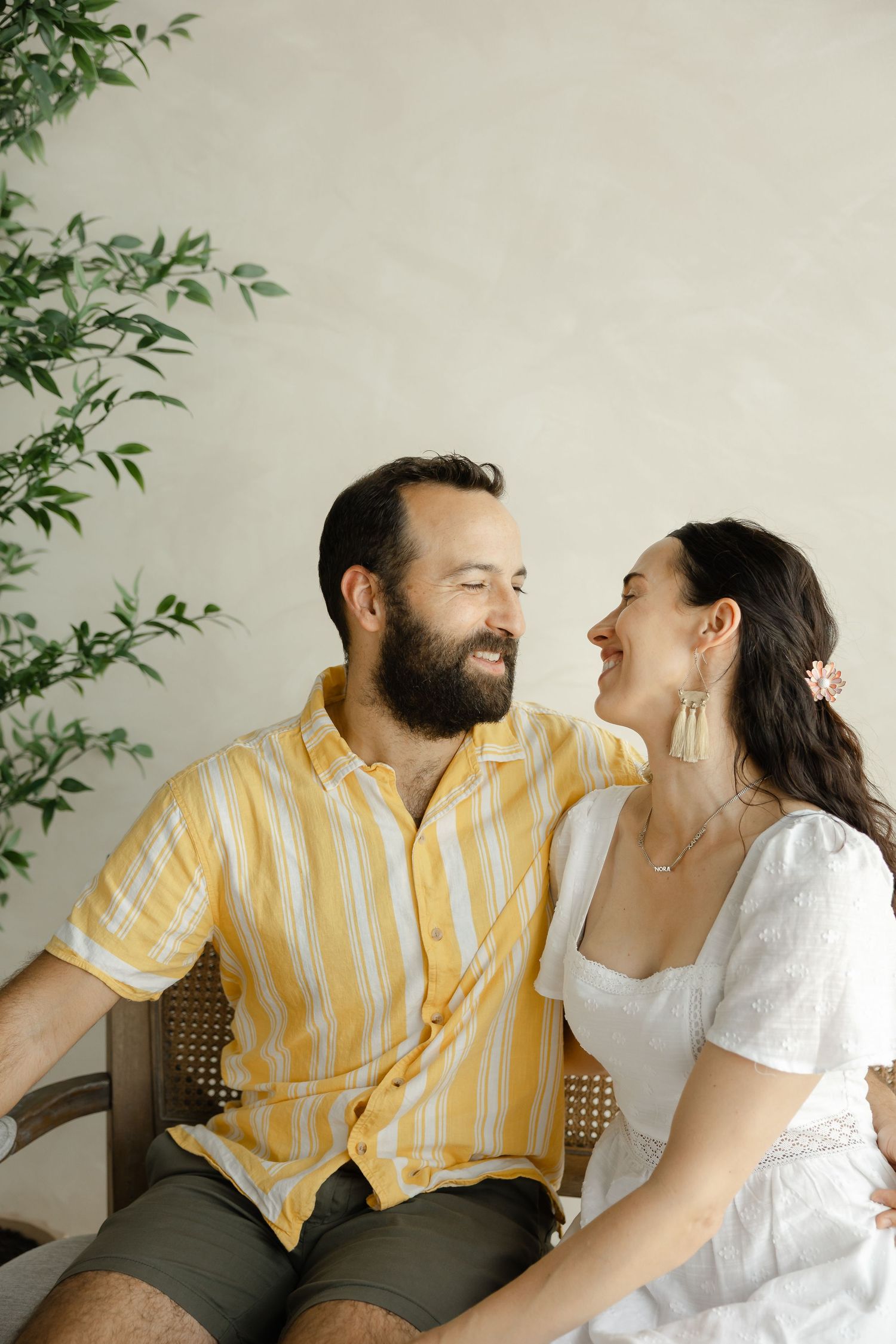 A smiling couple sits together, man in yellow striped shirt and woman in white dress, sharing a joyful moment indoors. Roanoke, VA
