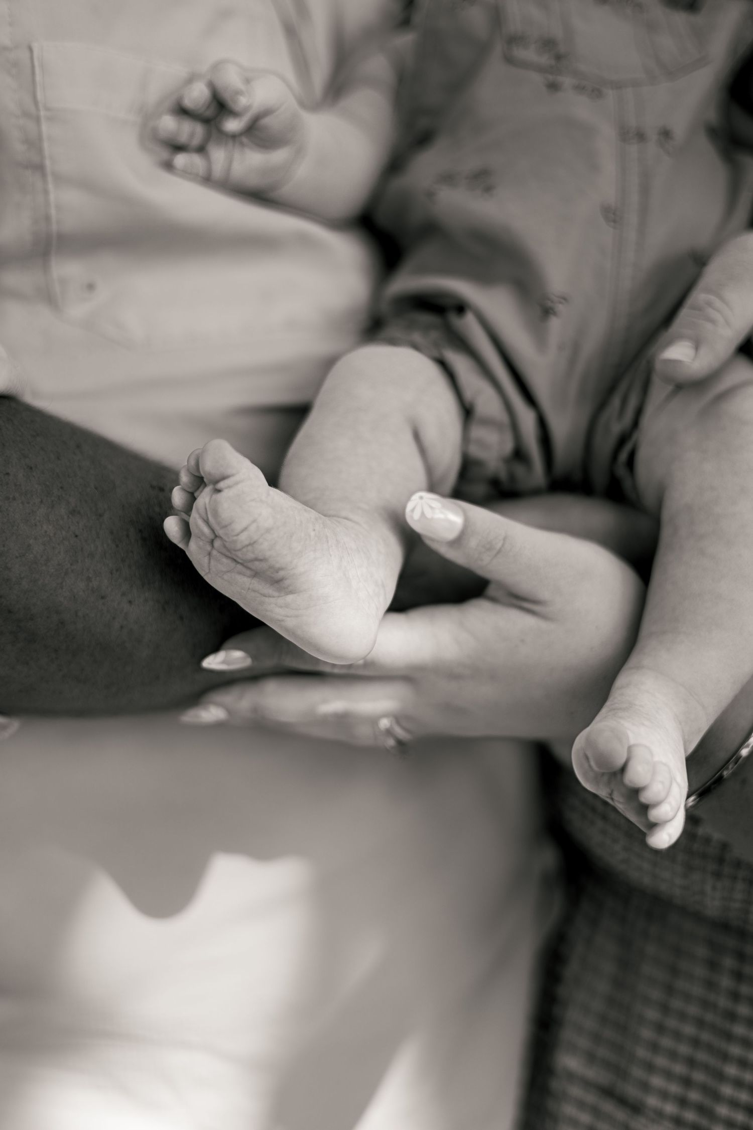 Black and white photo of an adult gently holding a newborn baby's tiny feet in their hands.