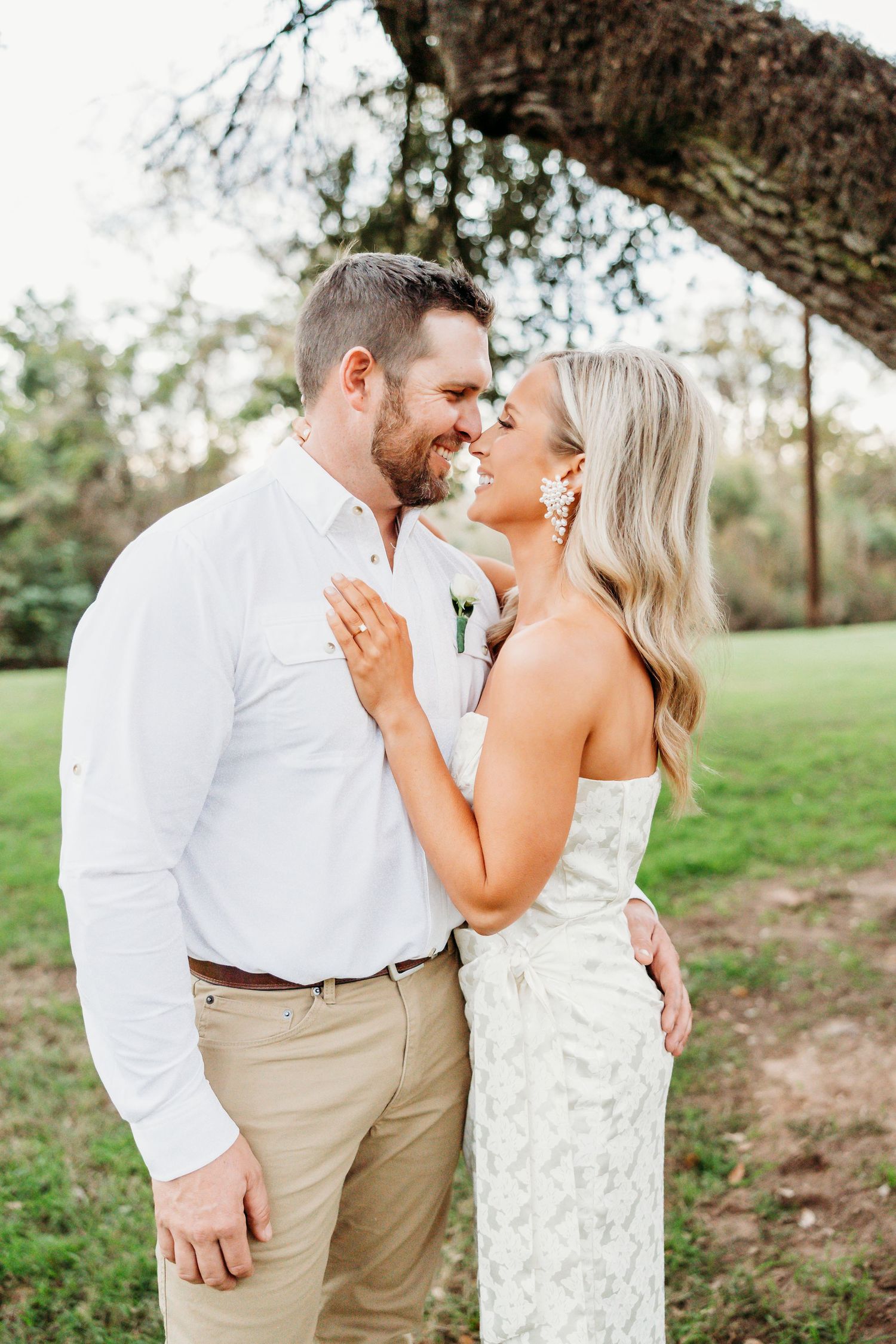 A couple in coordinating white and khaki outfits share romantic moments during an outdoor photo session.