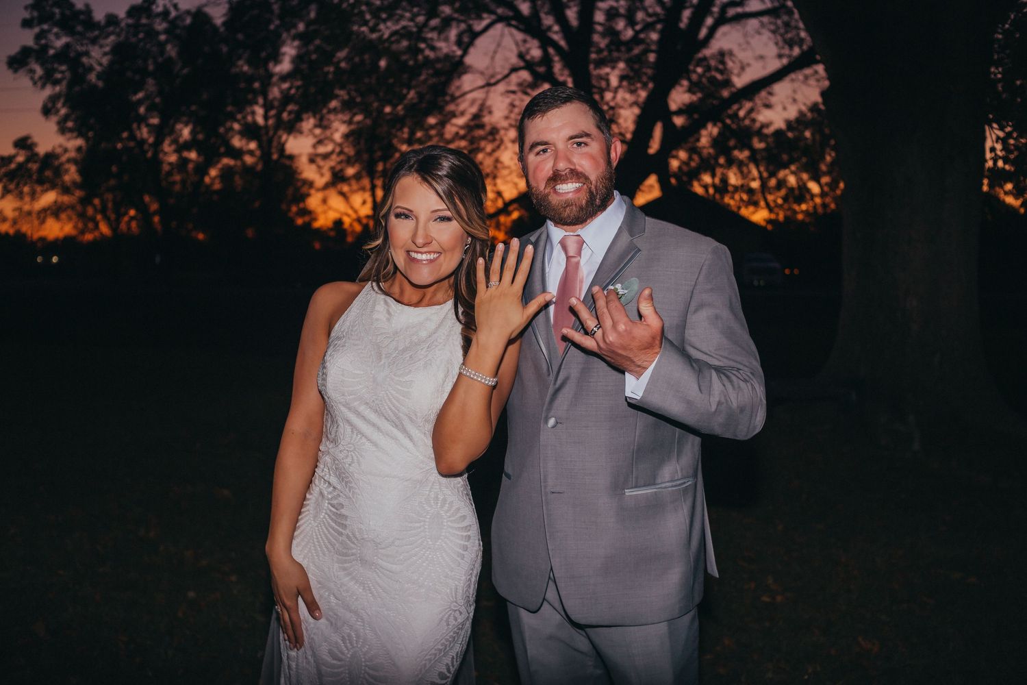 A couple poses together in front of a sunset backdrop during a romantic outdoor photoshoot.