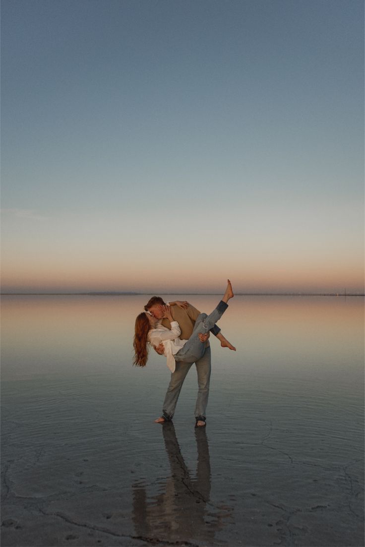 A sequence of silhouettes bending backwards at sunset on a reflective salt flat surface creating mirror-like reflections.