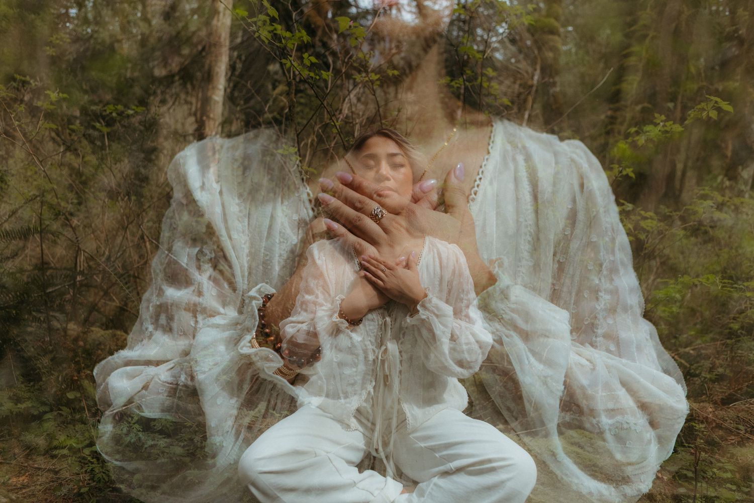Ethereal portrait of a woman in white lace dress standing in a dreamy forest setting with soft natural lighting.