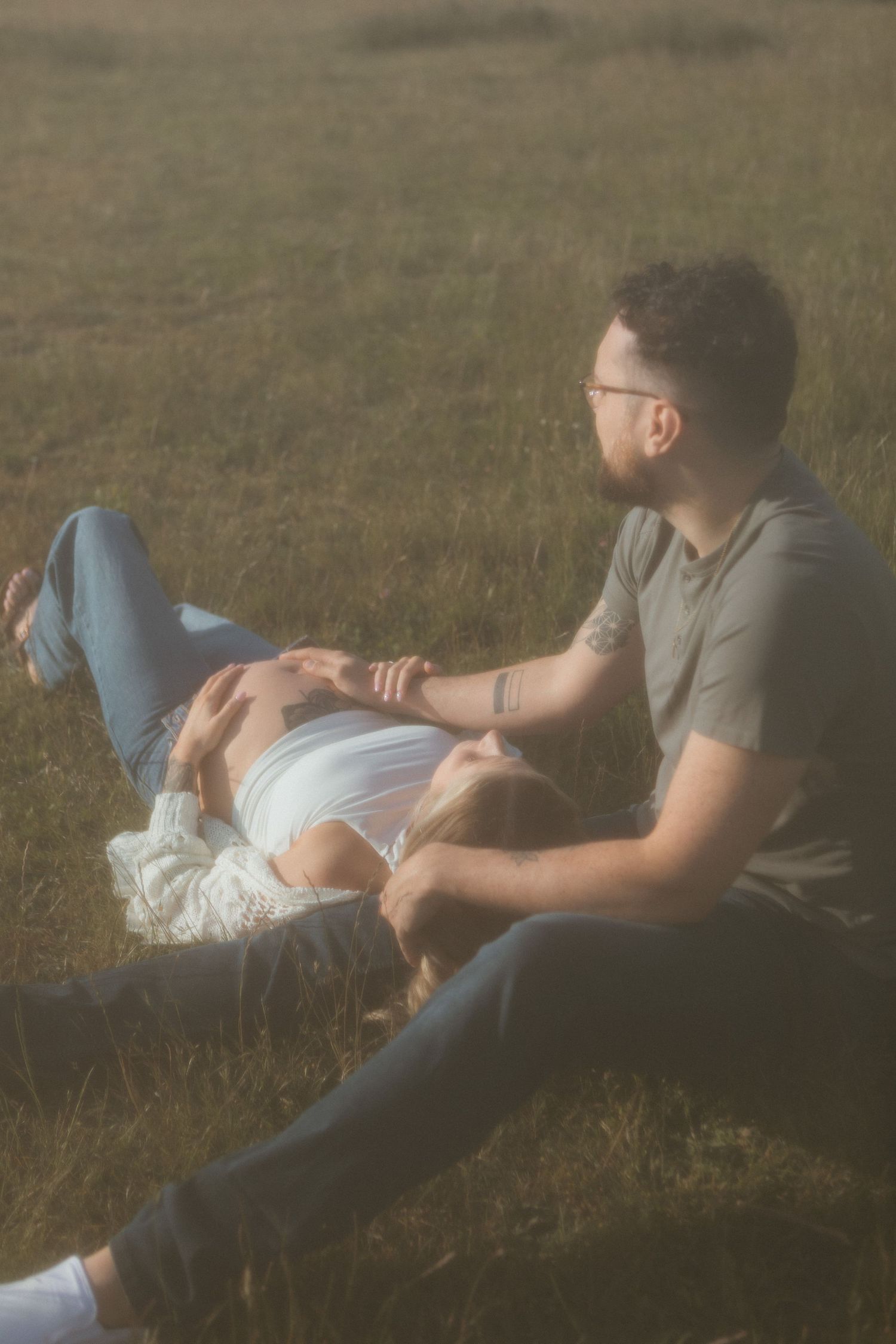 Intimate outdoor portrait session in a grassy field during golden hour.