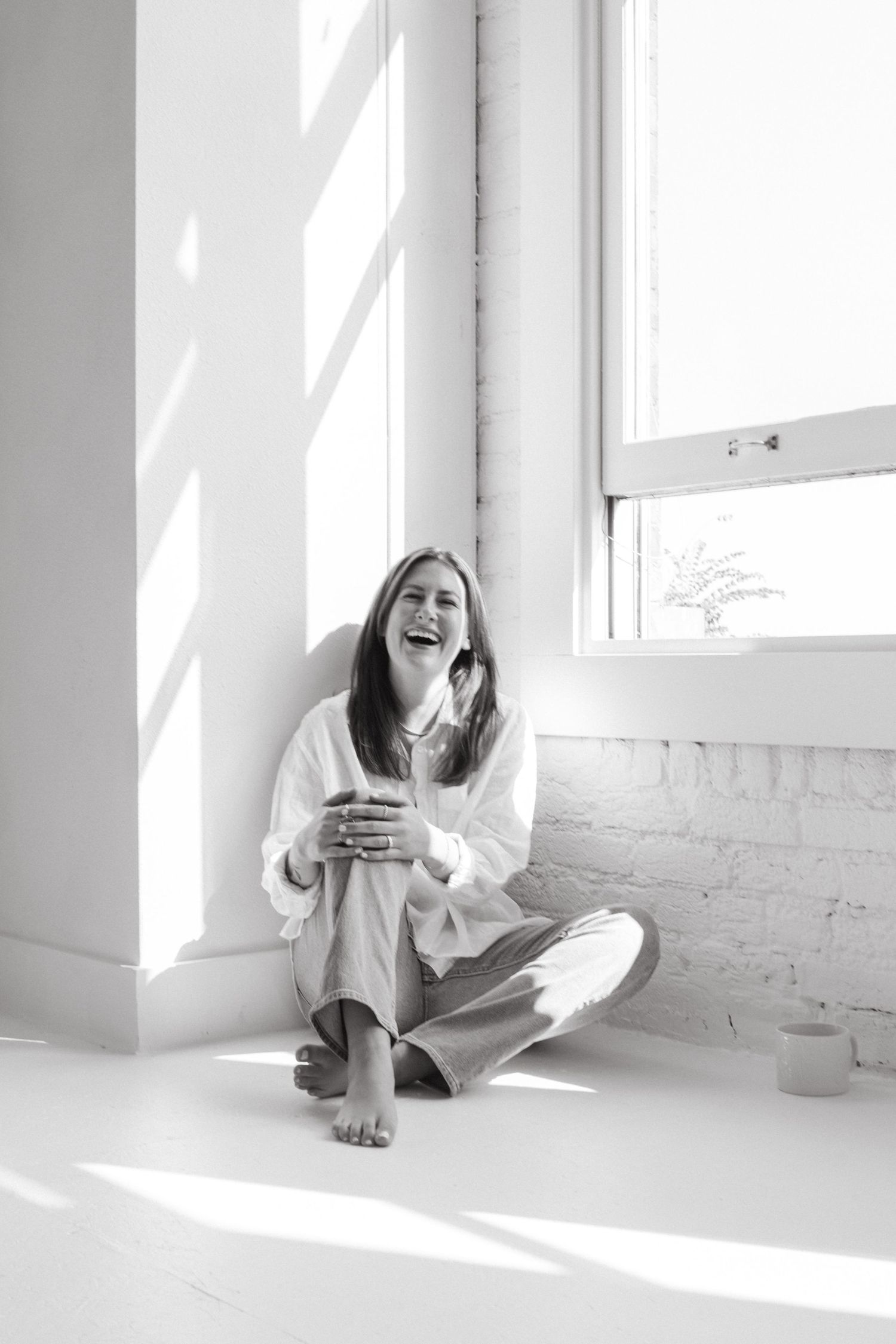 A series of black and white photos showing joyful expressions and movement in a bright sunlit room with white walls.