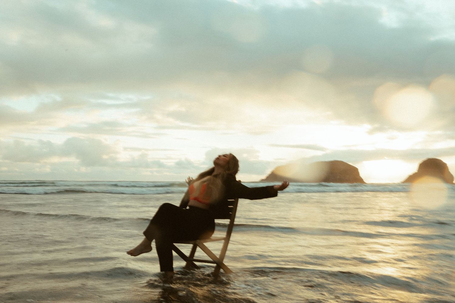An elephant joyfully plays in ocean waves at sunset, splashing and cooling off in the golden-lit seawater.