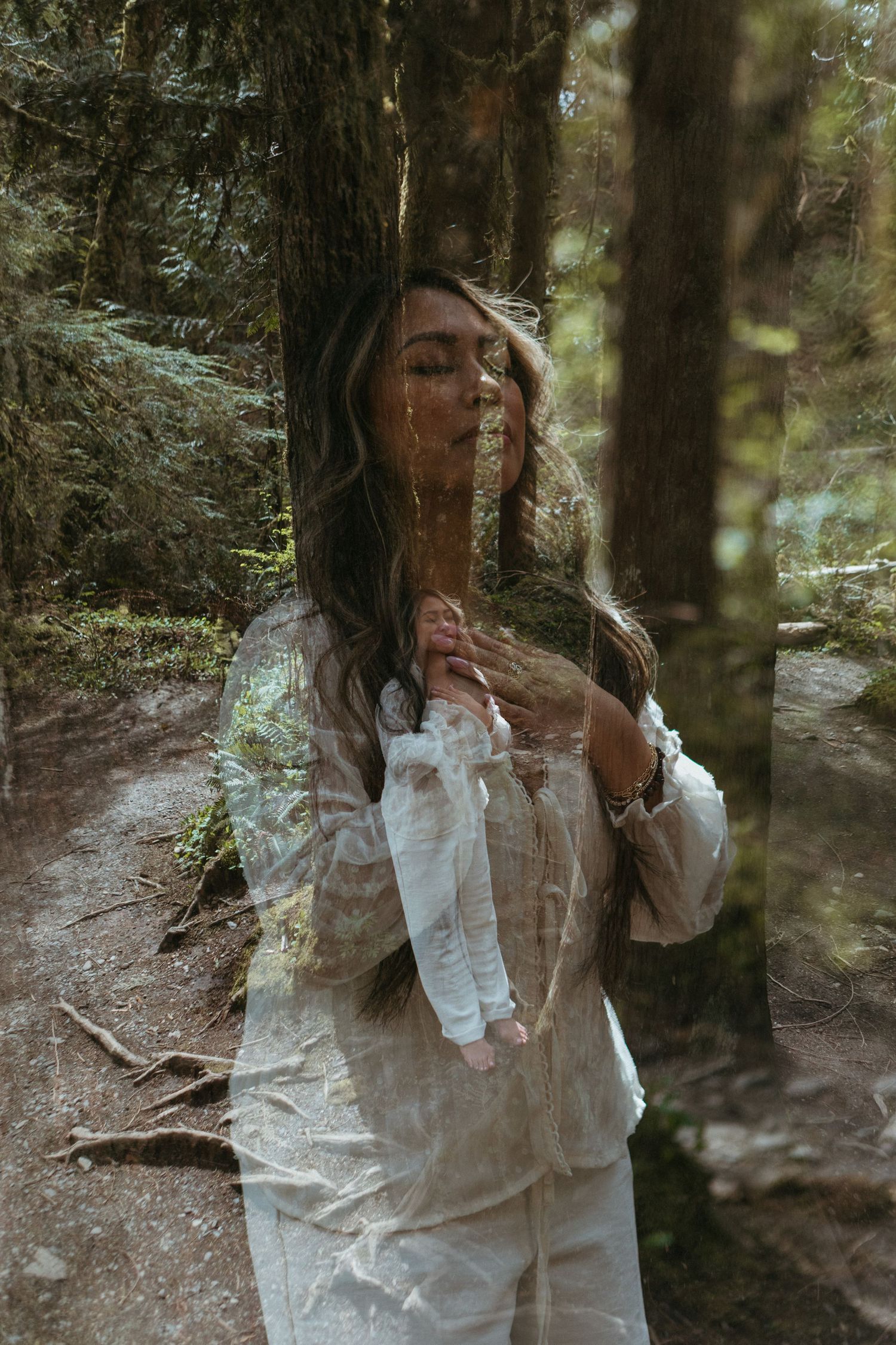 A person in a white dress stands among trees in a misty forest setting creating a dreamy ethereal atmosphere.