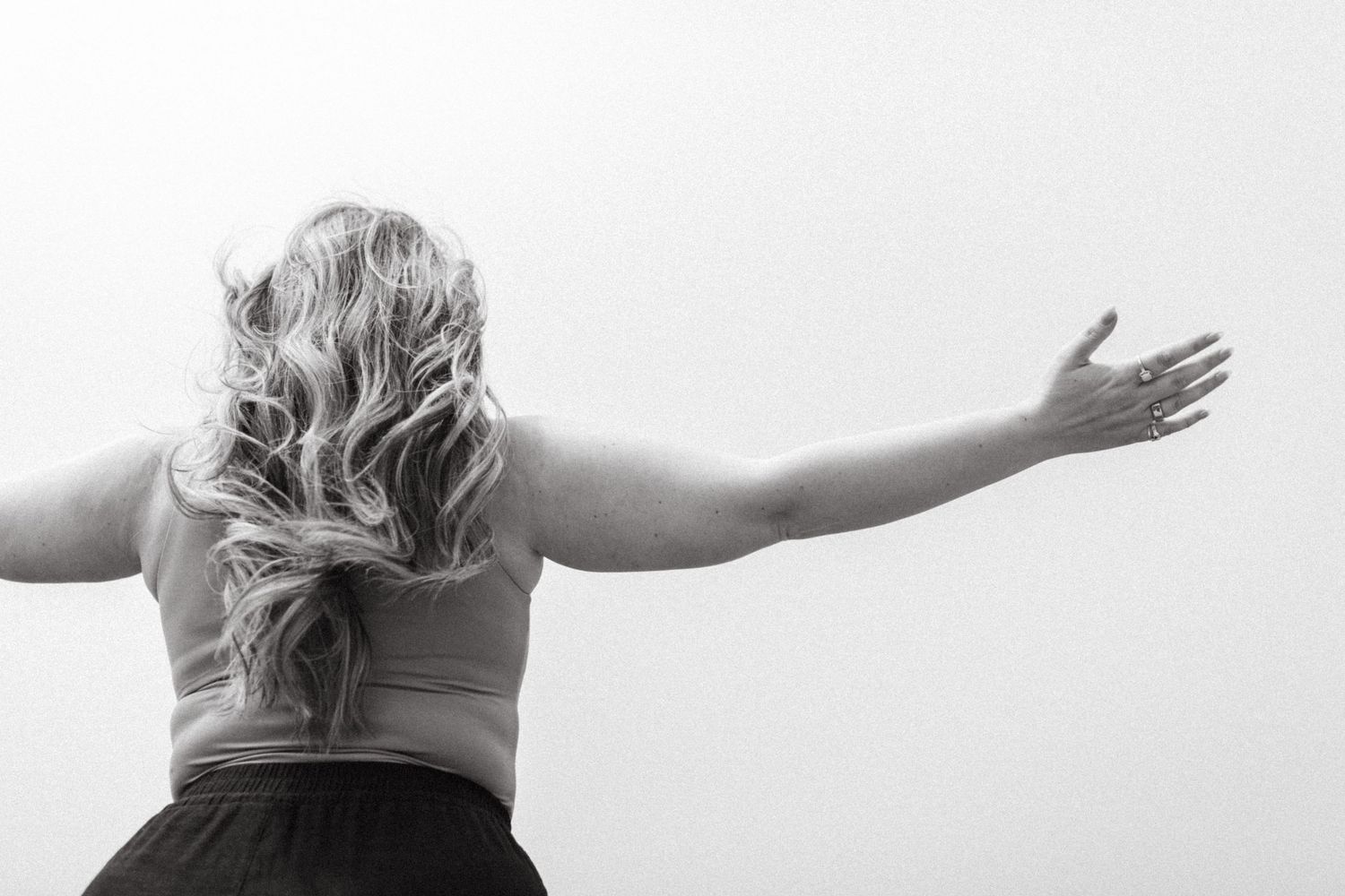 A figure stands with arms outstretched against a white background in a dramatic black and white pose.