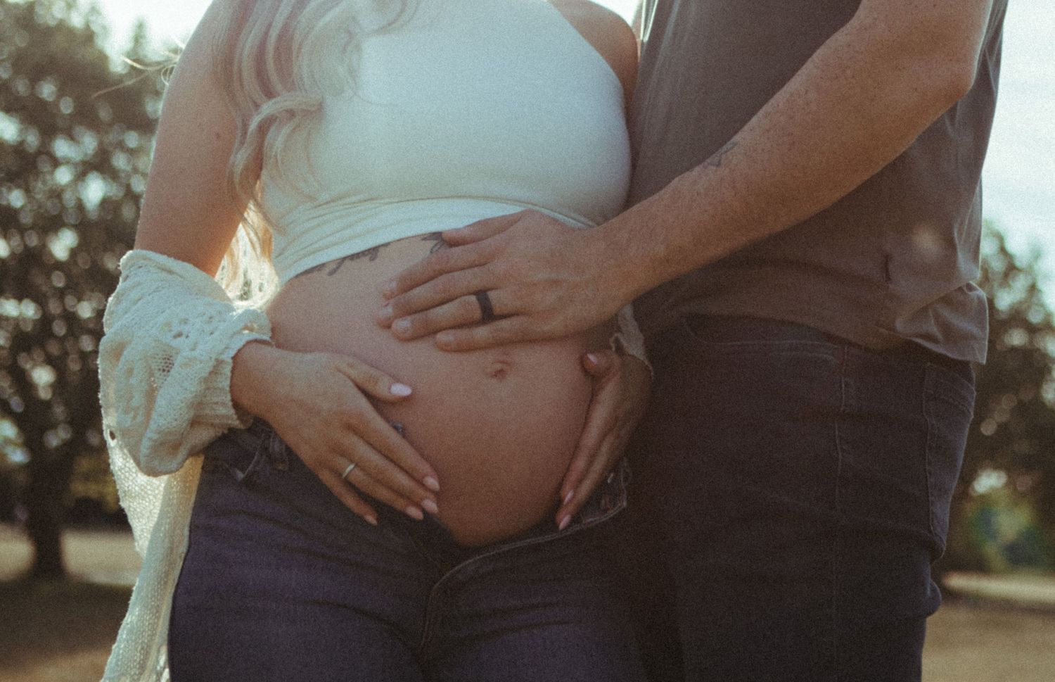 Maternity photo series showing close up shots of pregnant belly with hands lovingly cradling the bump in natural light.