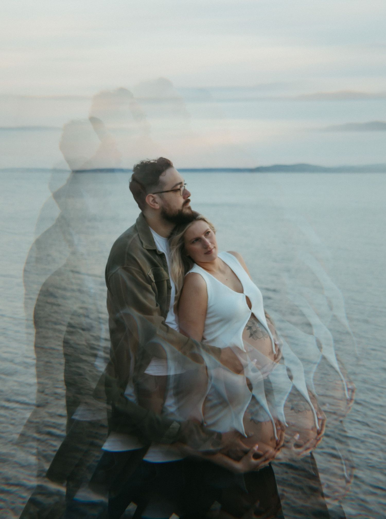 Multiple exposure photo of a couple embracing by a serene waterfront at dusk.