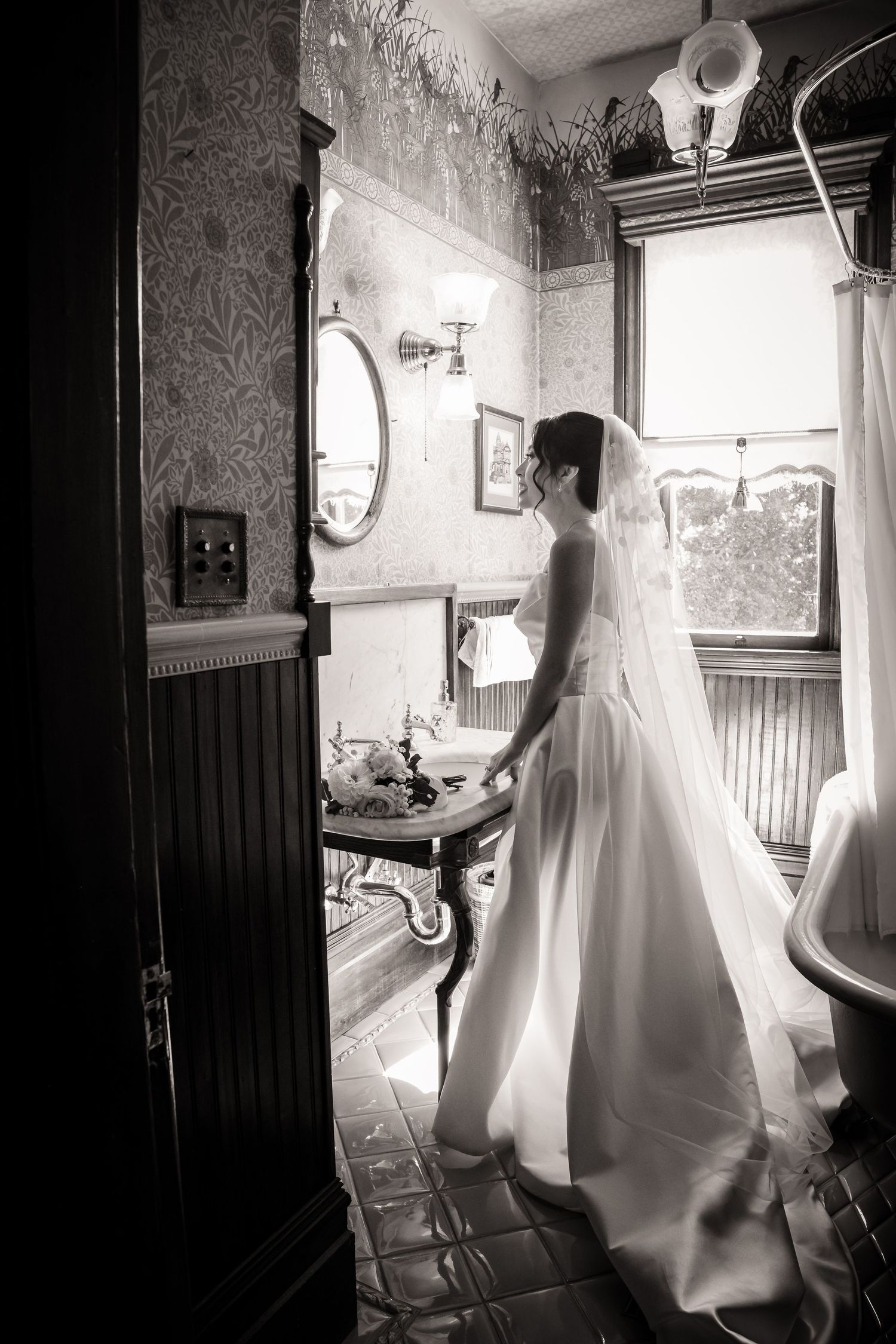 A black and white photo showing a bride in her wedding dress in the historic brehaut house in alameda California