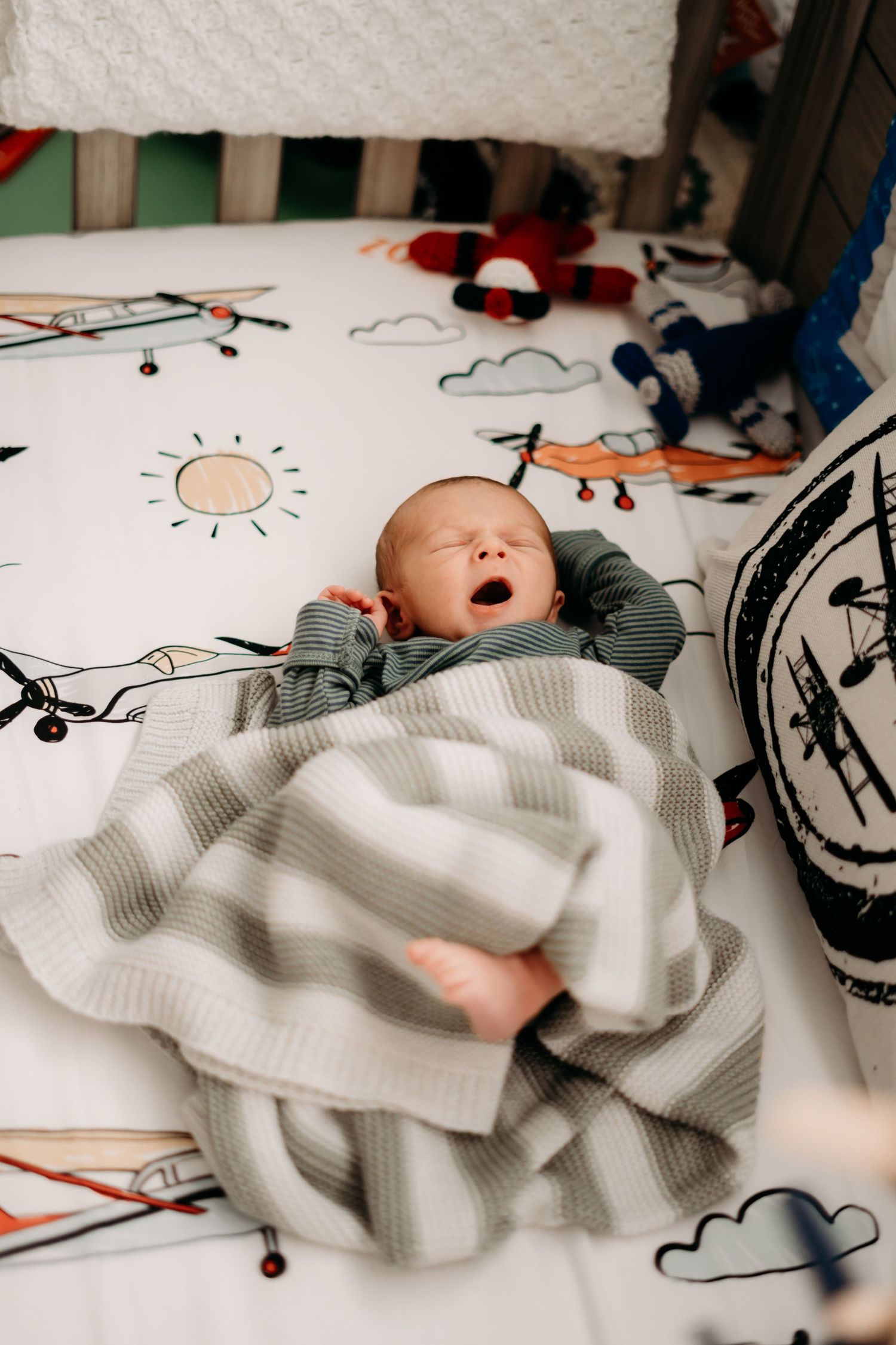Baby sleeping on white blanket in crib, yawning during in home lifestyle newborn photo session in Tacoma, Wa.