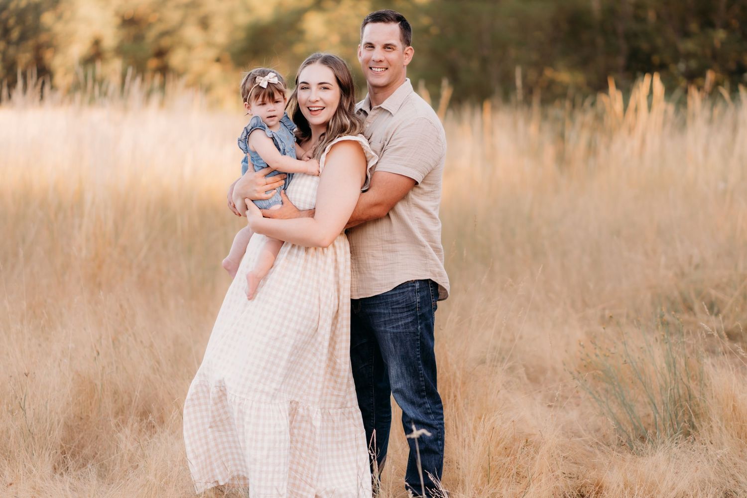 A family embraces together in a sunlit field of tall golden grass during sunset during family photos in Tacoma, Wa.