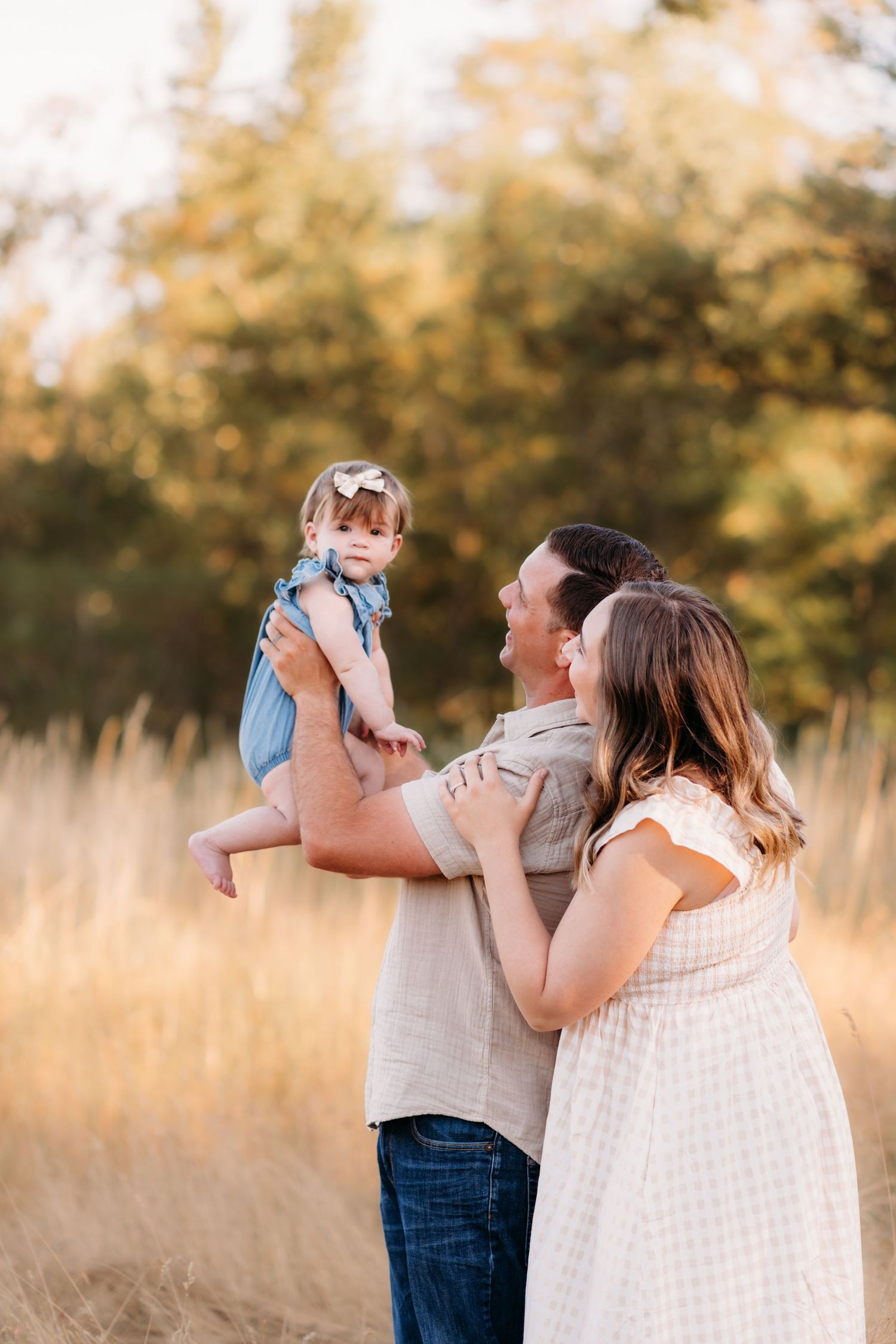 A family shares tender moments in a sunlit field with tall grass during golden hour during summer family photos in Tacoma.