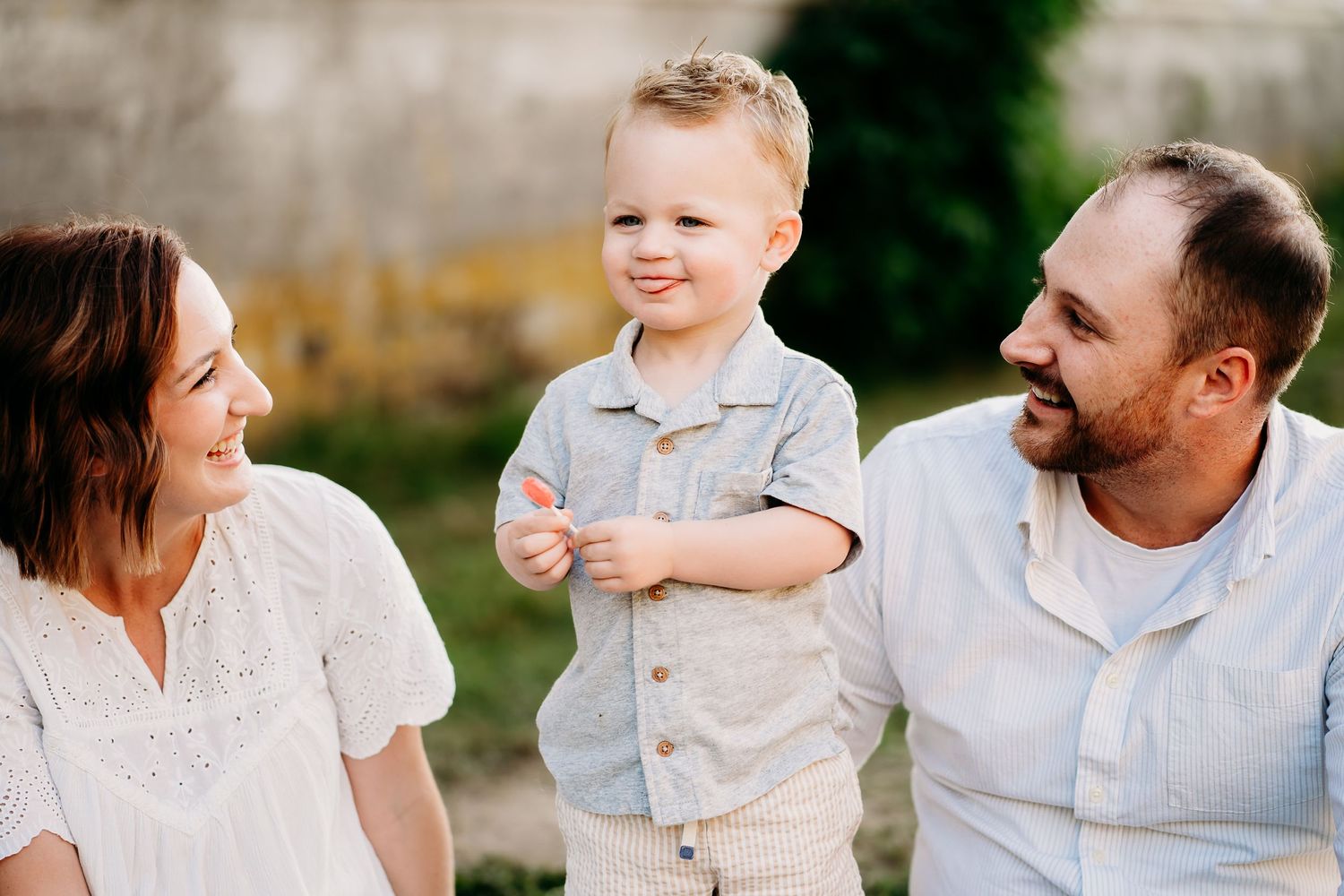 Family in casual summer attire sit together on a blanket next to rustic barn for summer family photos in Puyallup.