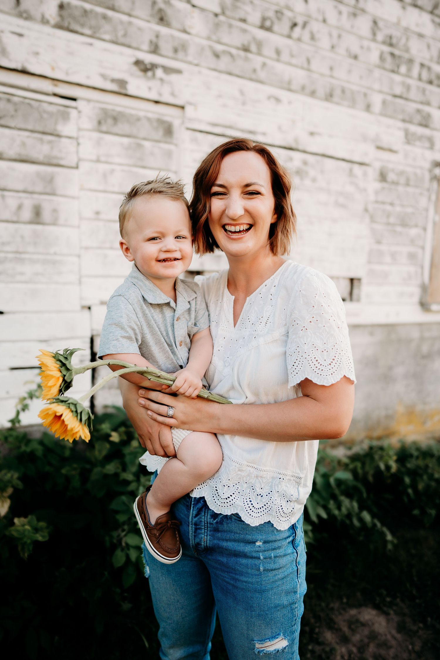 Mom hold toddler with sunflowers during summer photo session in Tacoma.