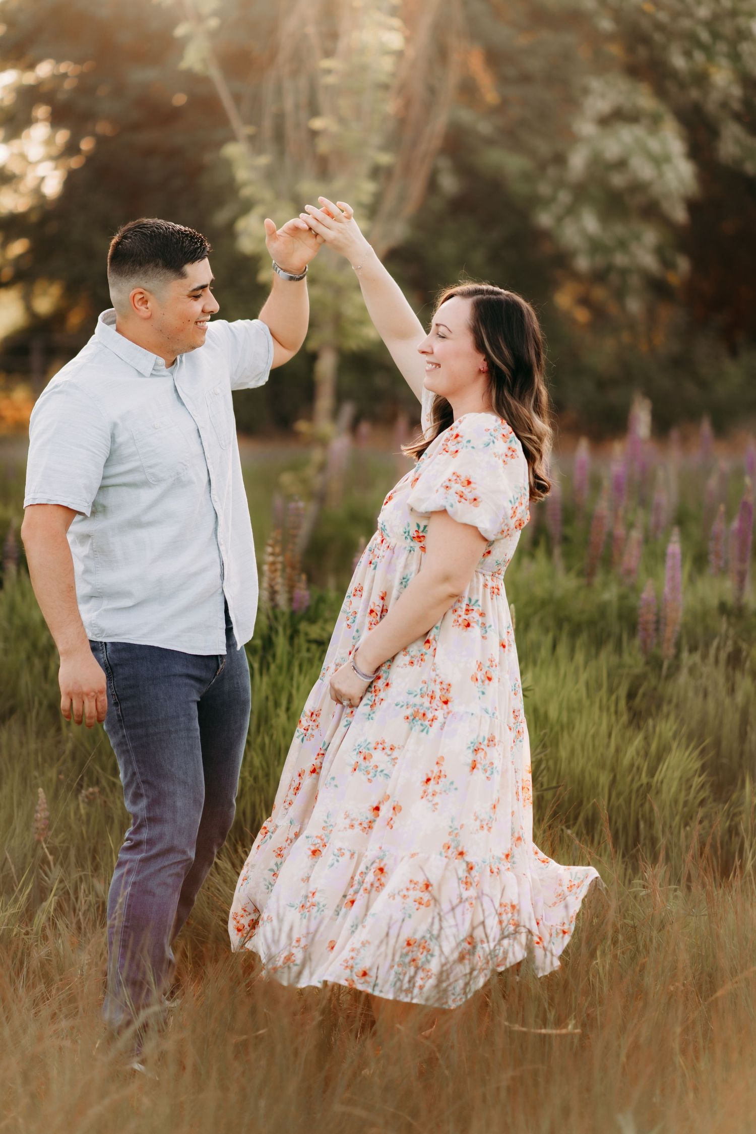 A couple dances together in a field of tall grass and wildflowers during a romantic sunset photoshoot in Puyallup, Wa.