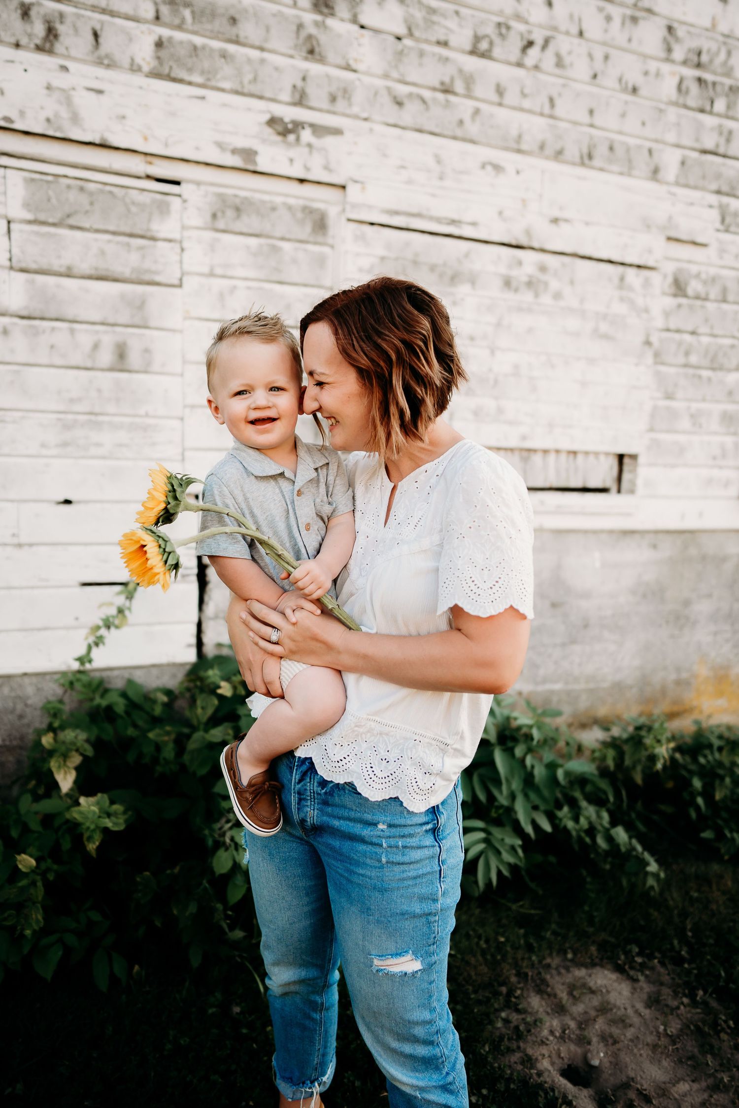 Mom hold toddler with sunflowers during summer photo session in Tacoma.