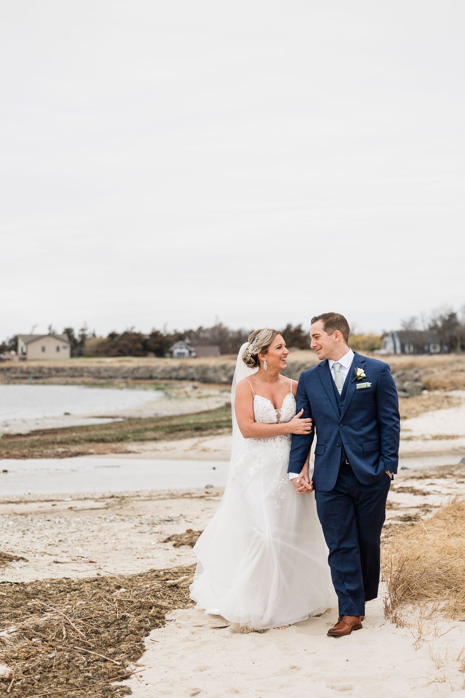 A romantic seaside wedding photo of a couple walking along the beach.