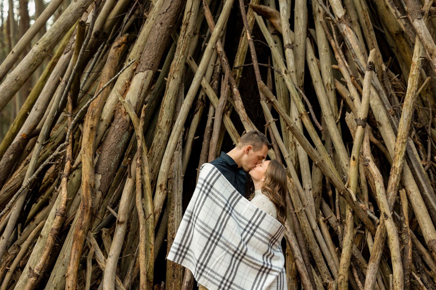 Creative portrait through stacked branches with person wearing plaid pattern.
