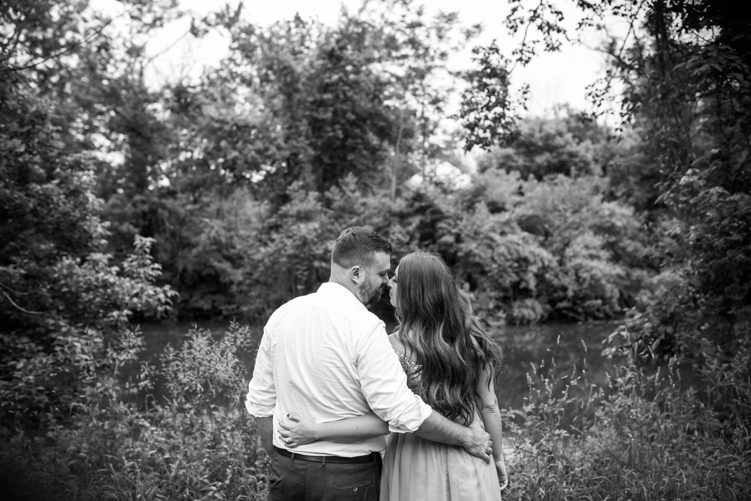 Black and white portrait of couple embracing in natural outdoor setting.